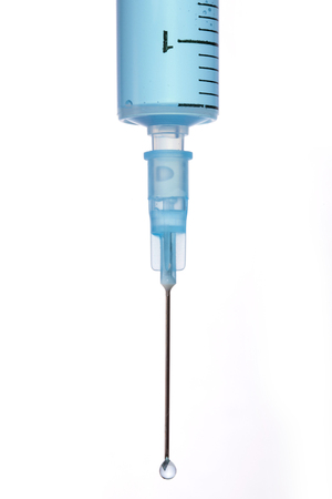 A laboratory syringe on white background is filled with blue solution.の写真素材