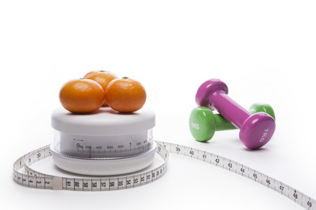 A tape measure, dumbbells, and oranges on white backgroundの写真素材