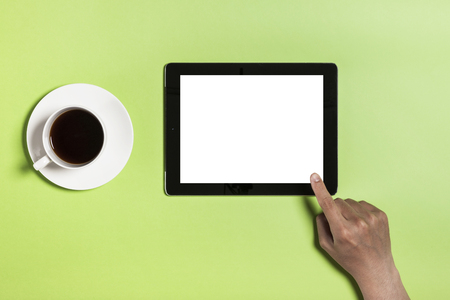 A cup of coffee and a tablet PC on green backgroundの写真素材