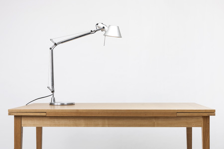 A brown wooden table with a desk lamp on white backgroundの写真素材