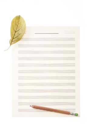 A fallen leaf and a pencil on a musical note paperの写真素材