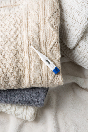 Objects photo for winter season. A thermometer on folded sweaters
