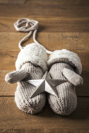 Objects photo for winter season. Gloves and a silver star on a wooden tableの写真素材