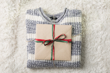 Objects photo for winter season. A Christmas present on a folded sweater on furry backgroundの写真素材