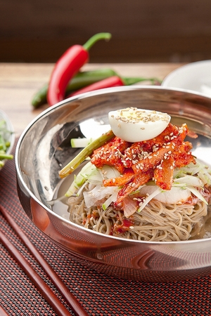Korean cold noodles with yeolmu kimchi, cucumber and spicy seasoningの写真素材
