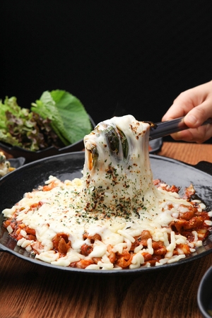 Korean spicy stir-fry with pork intestine, vegetables and cheese, close-up shotの写真素材