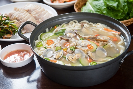 Korean handmade noodle kalguksu with manila clams, close-up shot with side dishesの写真素材