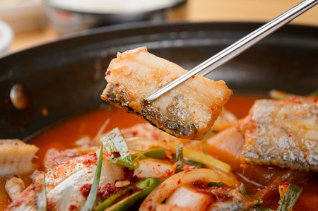 Korean spiced braised beltfish held with chopsticksの写真素材