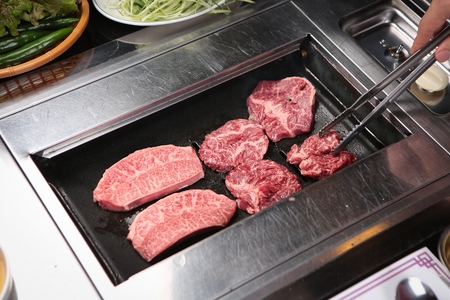 Korean barbecue, raw assorted beef parts grilled using tongsの写真素材