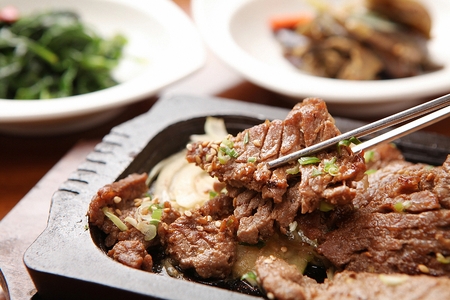 Korean cuisine, Gwangyang-style barbecued beef on grill pan, piece held with chopsticksの写真素材