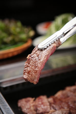 Korean barbecue, assorted beef parts grilled using tongs, close-up shotの写真素材