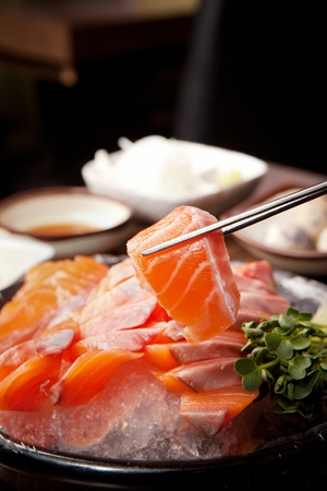 fresh salmon sashimi platter, a piece held by chopsticksの写真素材