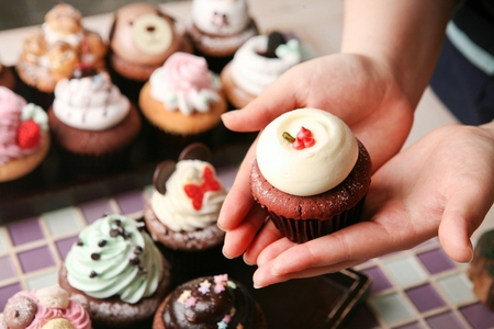 cute muffin on hands, assorted muffins with whipped creamの写真素材