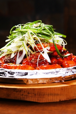 spicy barbecue Chicken with Korean rice cake topped with leeksの写真素材