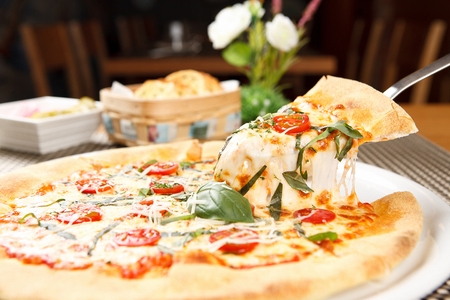 pizza knife lifting a slice from margherita pizzaの写真素材