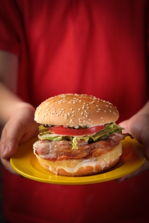 Hand carrying a yellow plate with a handmade burgerの写真素材