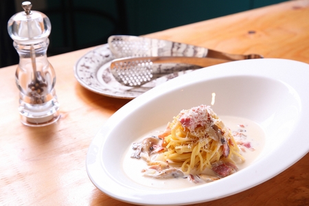 Mushroom bacon carbonara pasta on white plate, on a wooden tableの写真素材