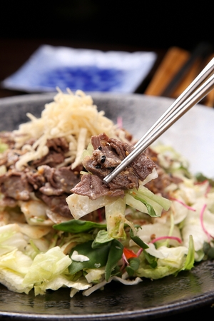 beef salad held with chopsticks, close-up shotの写真素材