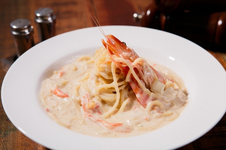 Shrimp cream pasta on a white plate, on a wooden tableの写真素材