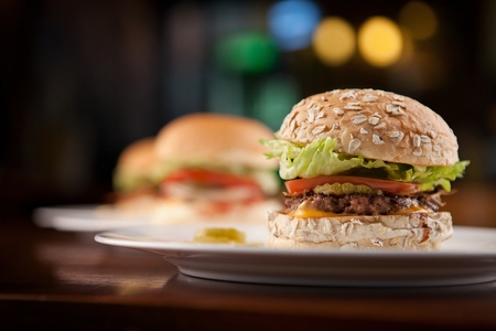Three handmade burgers on white plateの写真素材