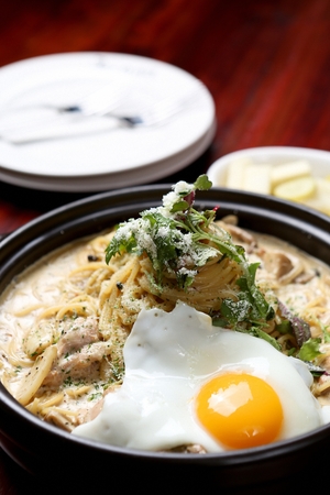 Mushroom chicken pasta with egg, on a black plateの写真素材