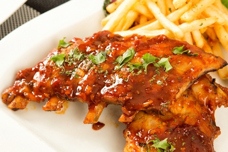 Barbecue pork rib and french fries, on a white plateの写真素材