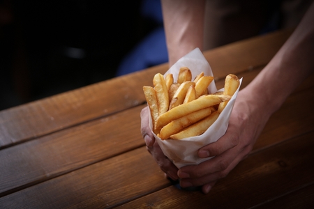 Hand grabbing french fries in a paper packageの写真素材