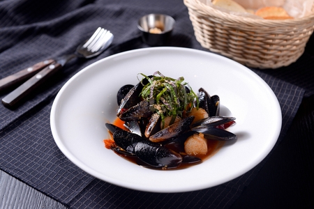 Mussels stew on a white plate, on a blue tableclothの写真素材