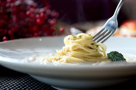 Broccoli carbonara pasta on a white plate, on a wooden table, close-up