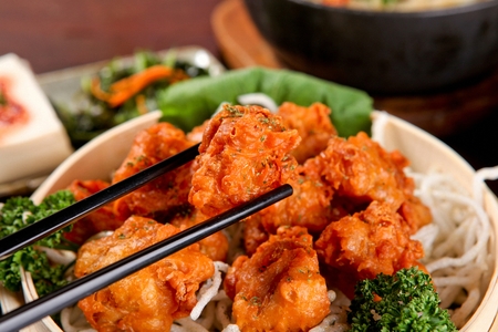 Chopsticks lifting a karaage on a porcelain, close-up