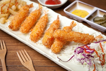 Fried shrimp and salad on a plate, on a table