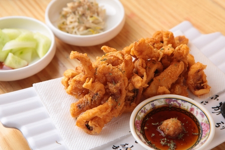 Fried squid in a long plate, on a wooden table