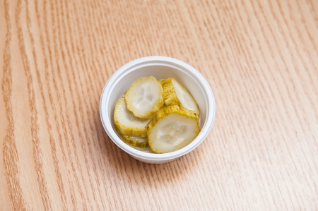 Cucumber pickle in a plastic trey, on a wooden tableの写真素材