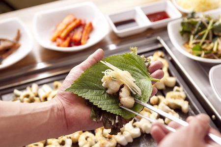 Chopsticks wrapping grilled eel in perilla leafの写真素材