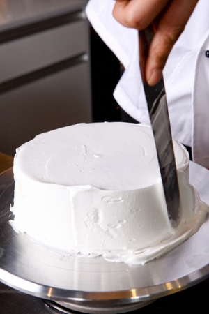 Baker putting whipped cream on cakeの写真素材