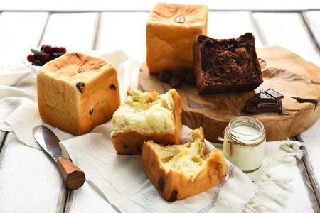 Bread with raisins, chocolate bread, knife on wooden cutting boardの写真素材