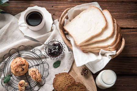 Blueberry bread, americano, strawberry jam, plain bread, milk on wooden tableの写真素材