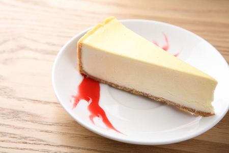 Cheesecake cake piece on white plate, on wooden table, close-upの写真素材
