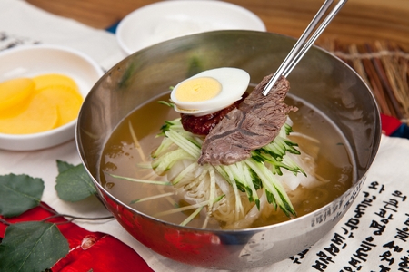 Bibim kuksu, a korean noodle dish which mixes noodles, vegetables and spicy seasoning, with cucumber, boiled egg and boiled beefの写真素材