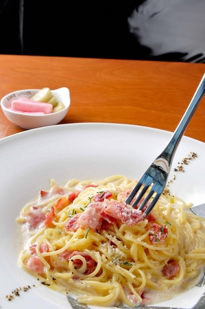Fork lifting carbonara pasta in white plateの写真素材