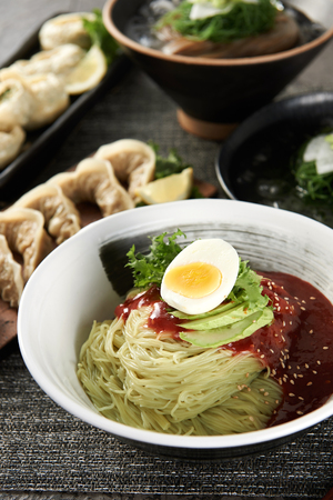 Korean cuisine Bibim Naengmyeon, chilled buckwheat noodles garnished with cold slices of beef, fresh skate, and radish or cucumber. Served with a spicy gochujang mixing sauceの写真素材