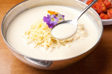 Chopsticks grabbing Kongguksu, korean noodle cuisine, broth is made of grated beans; served with...