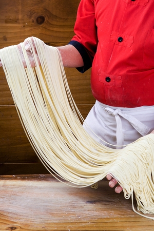 Chef's hand making handmade noodles by hitting the dough with his handsの写真素材