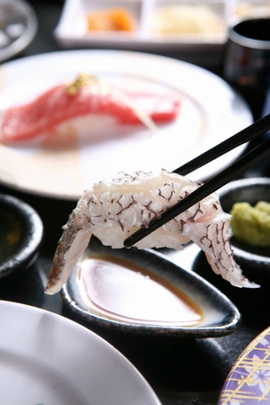 Chopsticks picking up sea bream sushi, a Japanese cuisineの写真素材