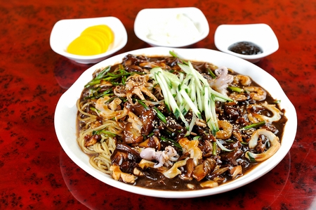 Jaengban Jjajang, chinese style korean black bean paste noodles with cucumber, onions and black bean paste, on wide white bowlの写真素材