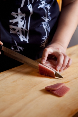 Japanese chef slicing raw tuna on a wooden cutting boardの写真素材