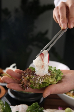 Sashimi dipped in red-chili pepper paste carried with a chopstickの写真素材