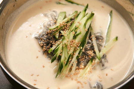 Kongguksu, korean noodle cuisine, broth is made of grated beans; served with cucumber, on silver bowlの写真素材