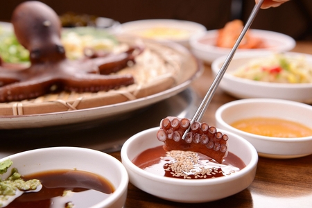 Chopsticks dipping thin octopus and boiled octopus in red pepper pasteの写真素材