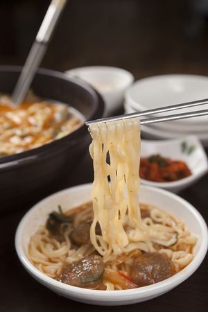 Chopstick lifting Korean cuisine, matzo balls kalguksu, spicy noodles with round potato doughの写真素材